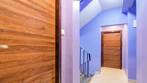 Un pasillo con puerta de madera, pared azul y suelo de baldosas.