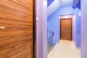 Un pasillo con puerta de madera, pared azul y suelo de baldosas.
