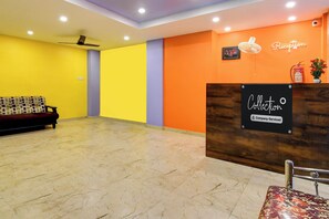Zona de recepción con mostrador, un reloj y un extintor en la pared.