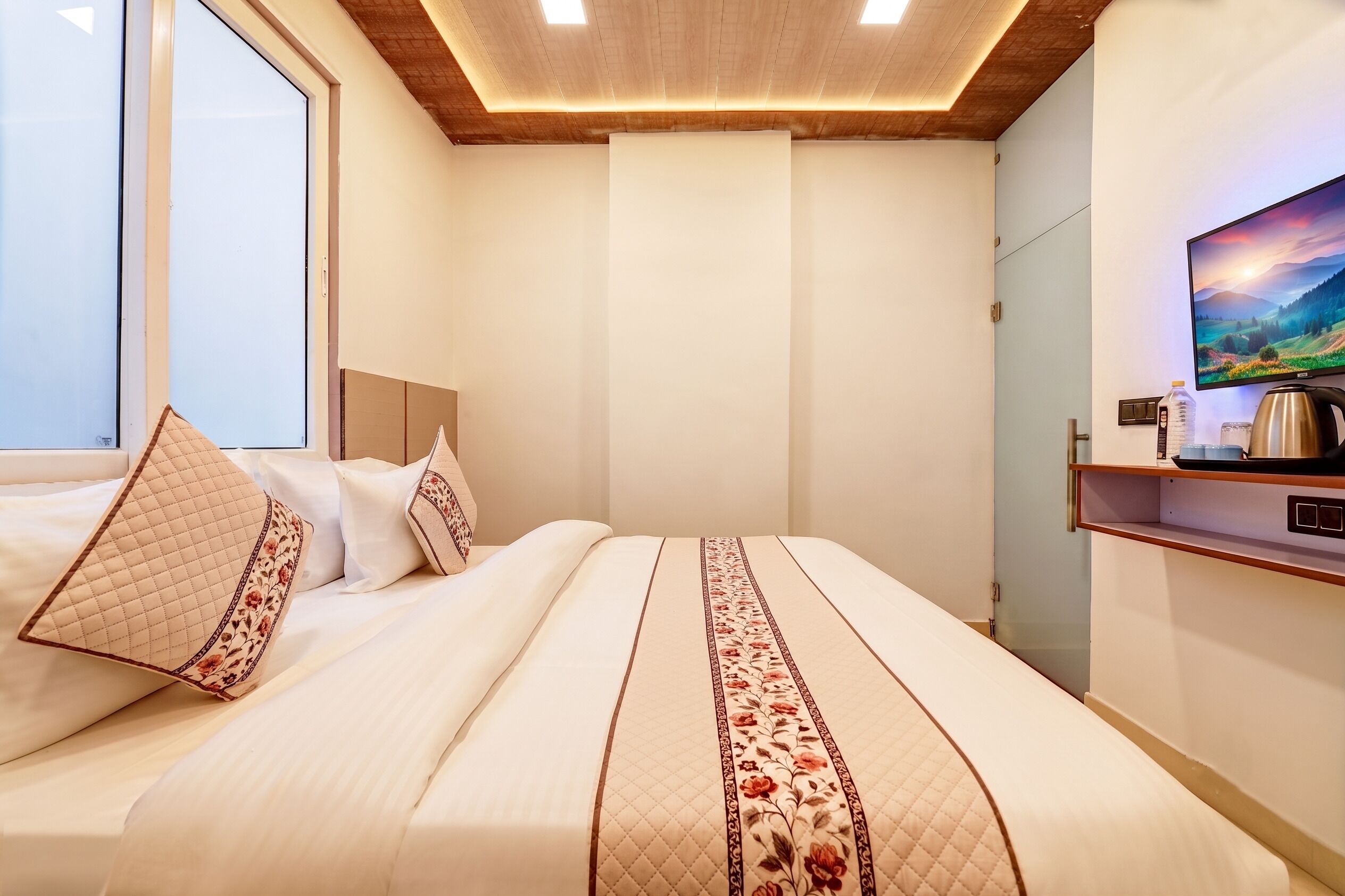 Een hotelkamer met een bed, een televisie en een raam.