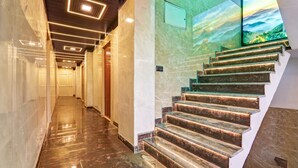 A modern interior with a marble staircase and a hallway leading to a door.