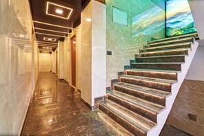 A modern interior with a marble staircase and a hallway leading to a door.