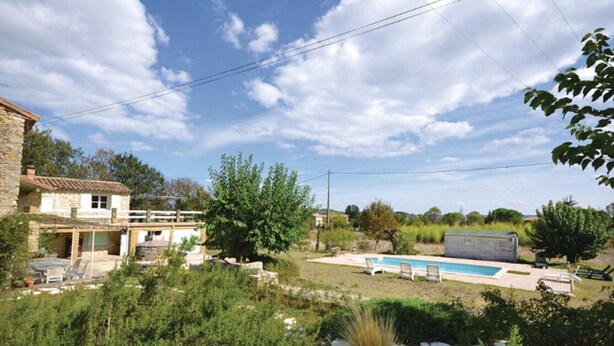 A stone building with a pool and outdoor seating.