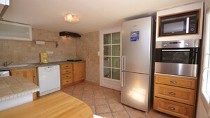 A compact kitchen with a refrigerator, microwave, oven, and a coffee maker.