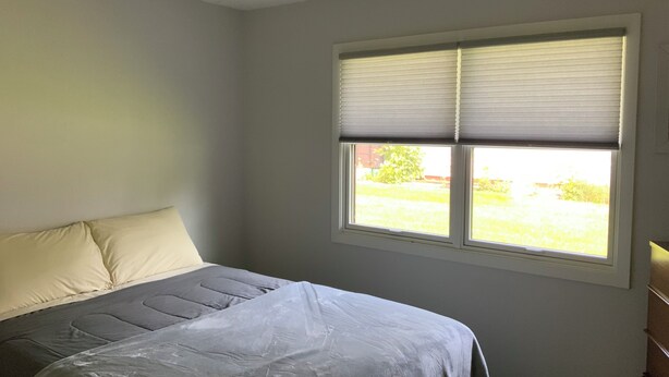 A bedroom with a bed, a window with blinds, and a view of the outdoors. - Newly remodeled. Quiet neighborhood 4 blocks from iconic Sturgis mainstreet (Sturgis)