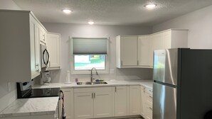 A modern kitchen with white cabinets, a stainless steel refrigerator, and a window with blinds. - Newly remodeled. Quiet neighborhood 4 blocks from iconic Sturgis mainstreet (Sturgis)
