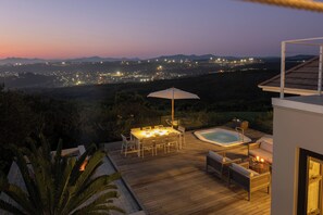 A deck with a hot tub, outdoor furniture, and a table with a canopy. - Sunhaven at Pezula (Knysna)