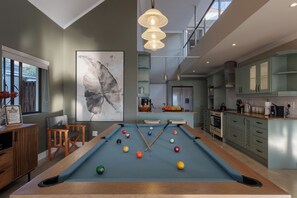 A modern kitchen with a pool table and a large abstract painting. - Sunhaven at Pezula (Knysna)