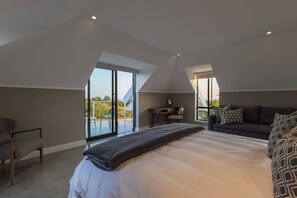 A modern bedroom with a large bed, a desk, and a sofa. - Sunhaven at Pezula (Knysna)