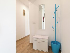A hallway with a white coat rack, a white cabinet, and a blue trash bin. - Elvix Nerja Centre B by Interhome (Nerja)