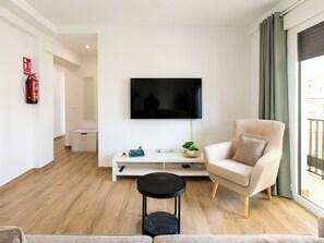 A modern living room with a flat-screen TV, a sofa, a coffee table, and a small side table with a plant. - Elvix Nerja Centre B by Interhome (Nerja)