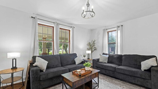 A living room with two dark sofas, a wooden coffee table, and a chandelier.