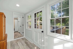 A hallway with white walls, wooden doors, and large windows with a view of the outdoors. - Cozy Getaway Near History, Hiking & Adventure (Bolivar)