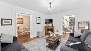 A modern living room with a fireplace, a dining area, and a staircase leading to another level.