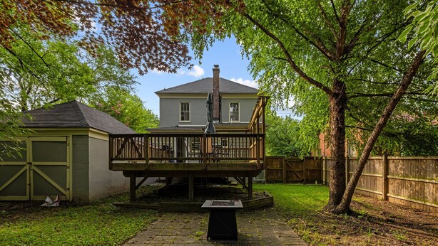 A backyard with a wooden deck, a brick fire pit, and a house in the background. - Cozy Getaway Near History, Hiking & Adventure (Bolivar)