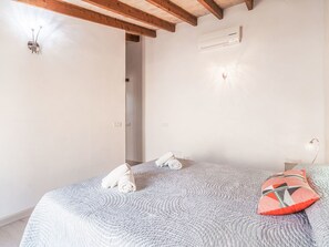 A bedroom with a bed, a wall-mounted air conditioner, and a wooden ceiling beam. - Can Tianet by Interhome (Randa)