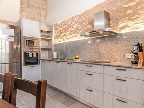 A modern kitchen with granite countertops, stainless steel appliances, and a stone backsplash. - Can Tianet by Interhome (Randa)