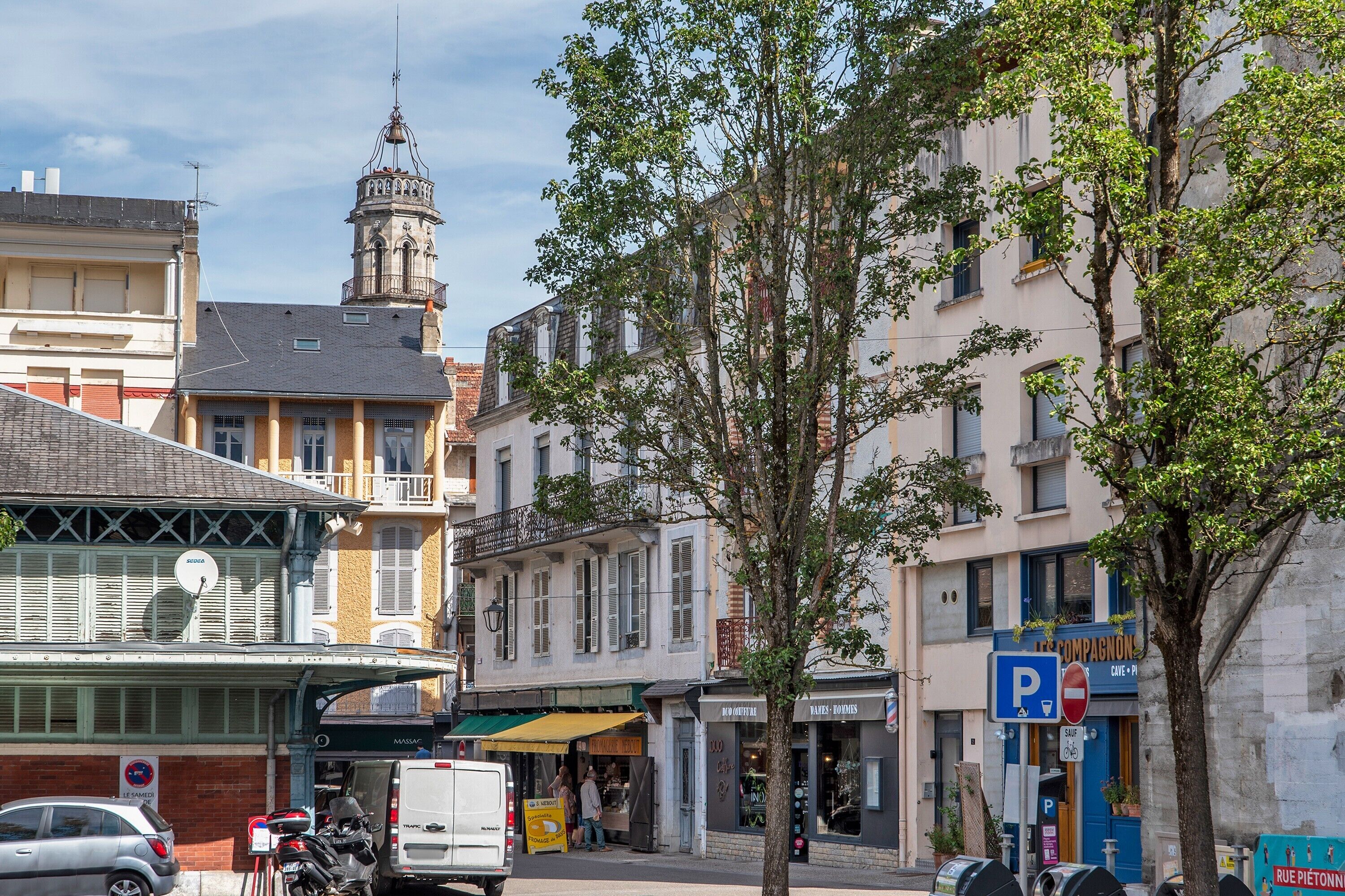 A street view with buildings, a bell tower, and a parking sign.