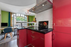 A modern kitchen with red cabinets, a black countertop, and a stainless steel range hood. - Apartment 'Le Bédat' with Mountain View, Balcony and Wi-Fi (Bagnères-de-Bigorre)