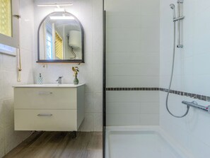 A bathroom with a white vanity, a mirror, a shower with a handheld hose, and a tiled floor. - Villa Pipa by Interhome (Deltebre)