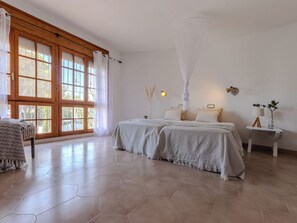A bedroom with a large window, a bed with two pillows, a bedside table with a lamp, and a chair. - Villa Pipa by Interhome (Deltebre)