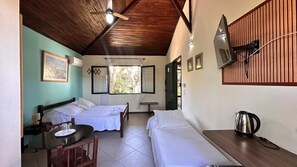 A room with two beds, a table, a chair, a ceiling fan, and a window. - Pousada Oceânica Búzios (Buzios)