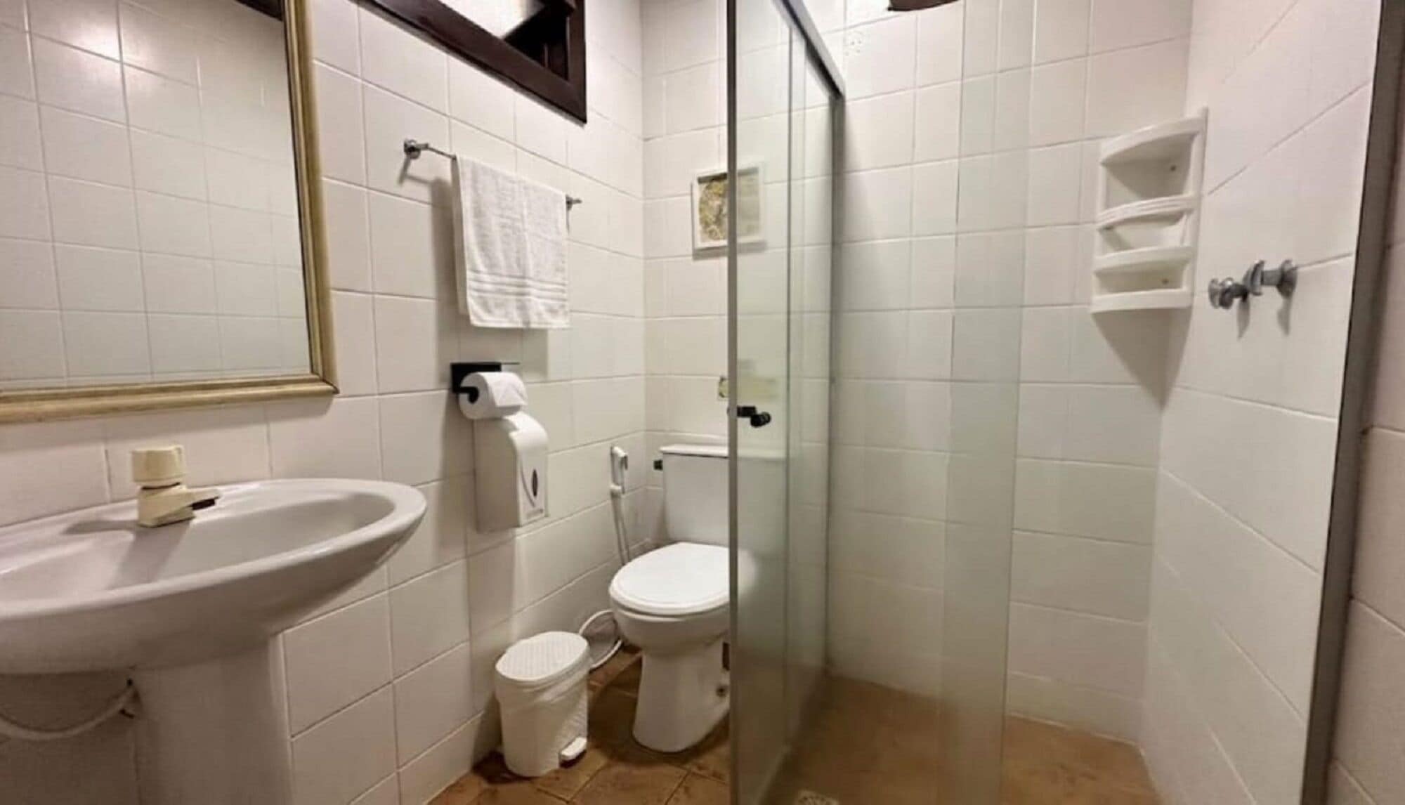 A bathroom with a sink, toilet, and glass-enclosed shower stall.
