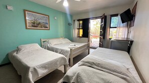 A room with two single beds, a painting on the wall, a television mounted on the wall, and a window with curtains. - Pousada Oceânica Búzios (Buzios)