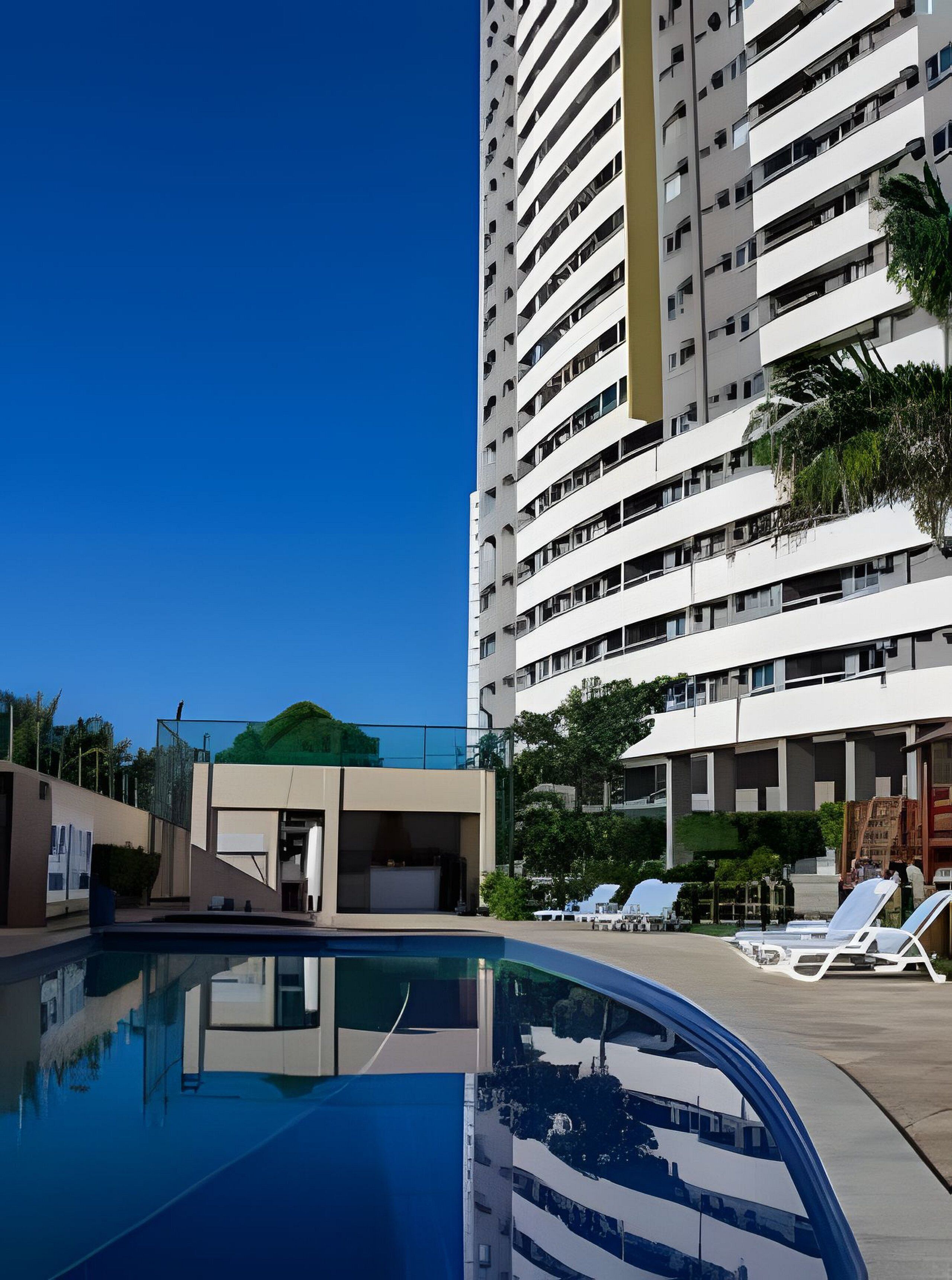 Um hotel moderno com piscina e espreguiçadeiras.