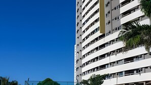 A high-rise hotel with a swimming pool and lounge chairs.