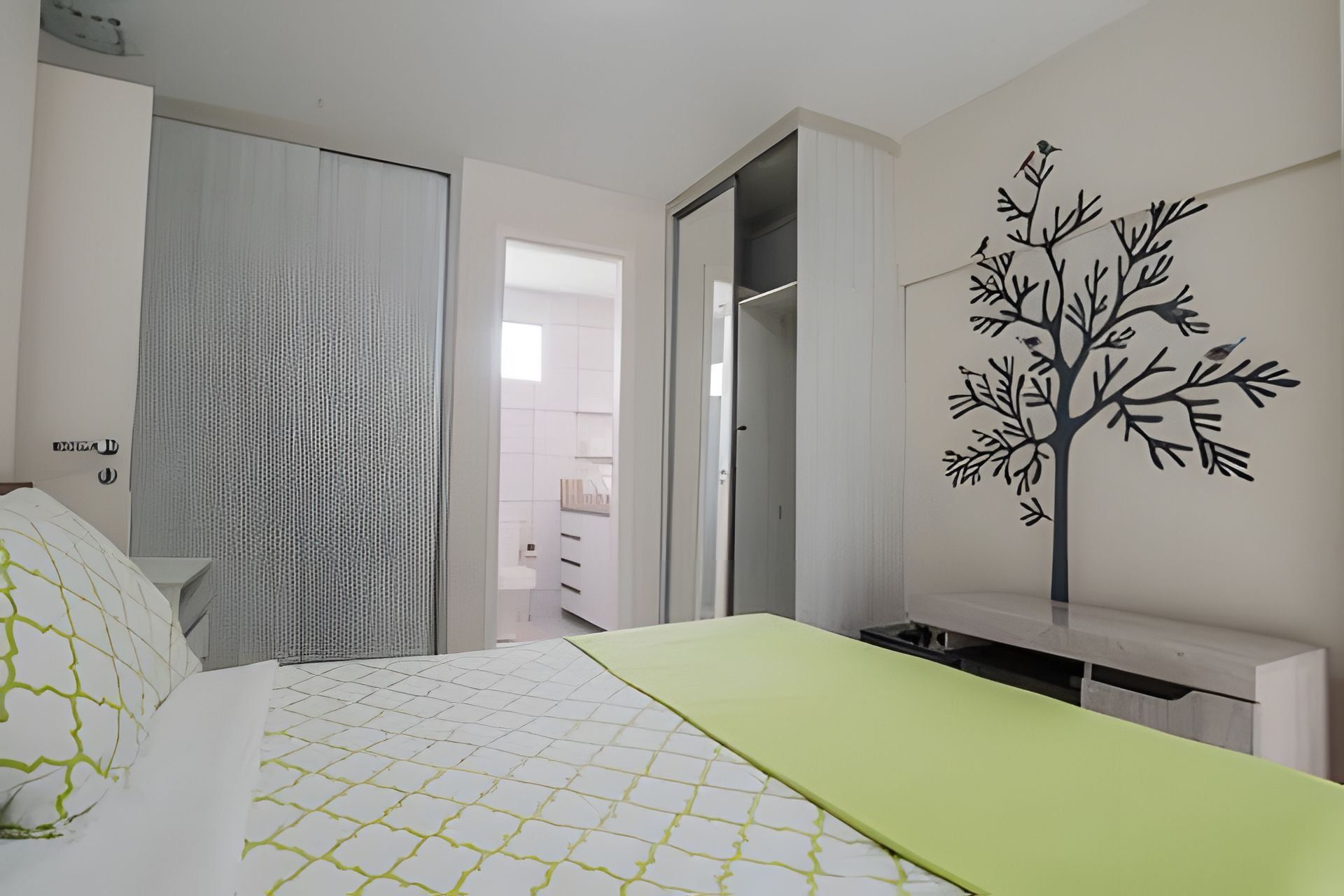 Quarto com cama, guarda-roupa e decoração de árvore na parede.