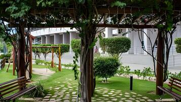 A covered outdoor area with a stone pathway, benches, and greenery.