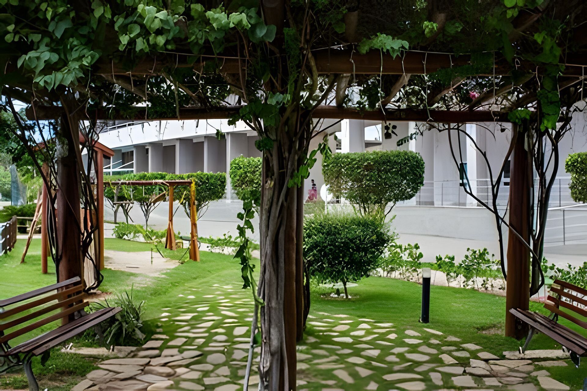 A covered outdoor area with a stone pathway, benches, and greenery.