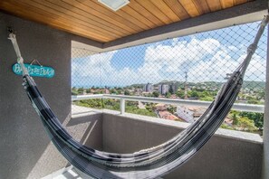 A hammock on a balcony with a view of a cityscape.