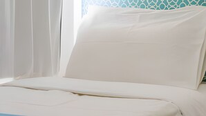 A bed with white bedding and a blue accent.