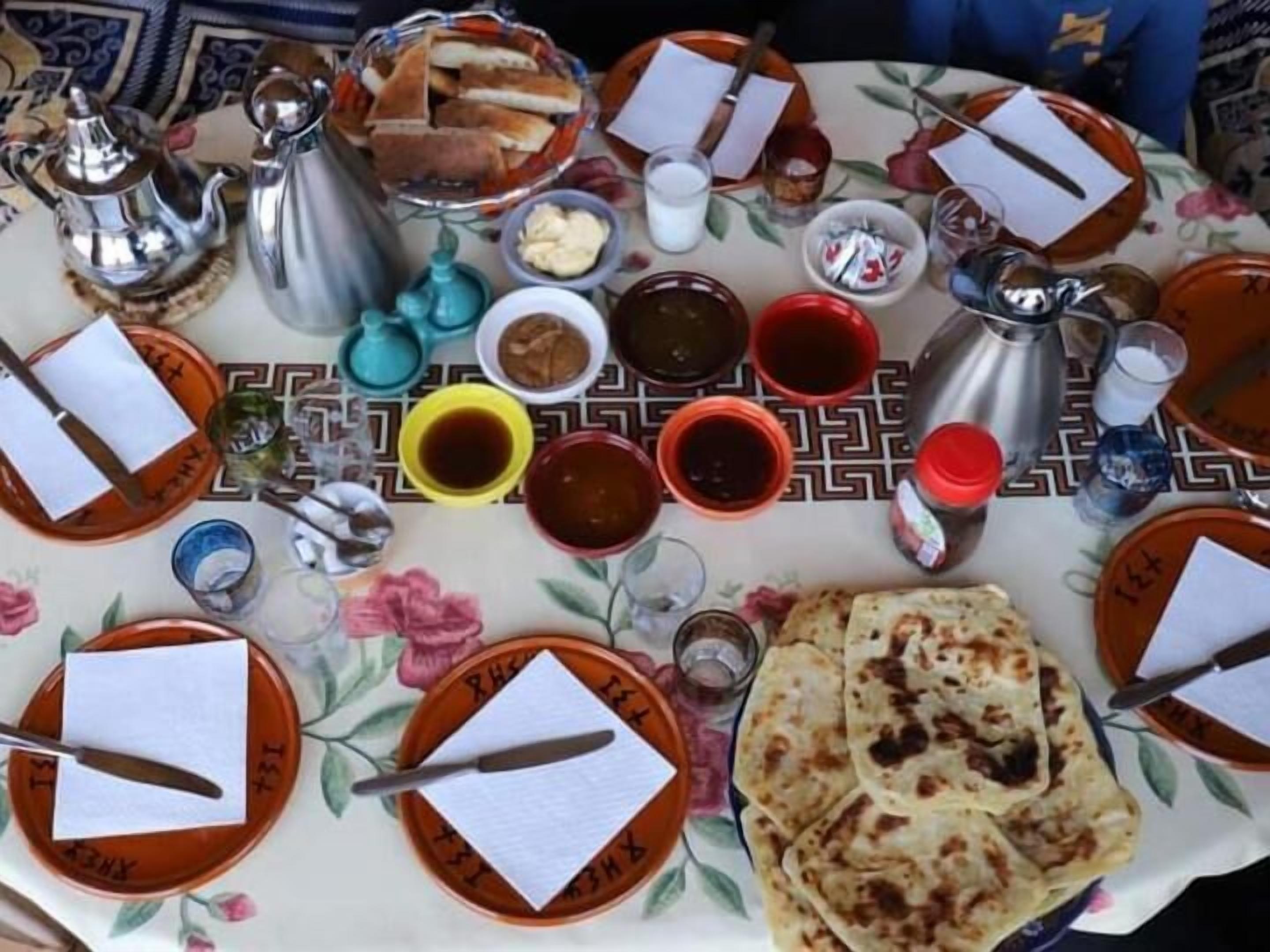 Une table dressée avec des assiettes, des couverts et divers plats, notamment des galettes et des condiments.
