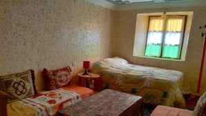 A room with two beds, a table, and a window with curtains.
