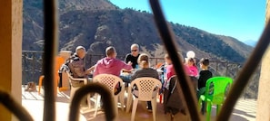 A group of people seated at an outdoor table with a mountainous backdrop. - Gite Gliz (Asni)