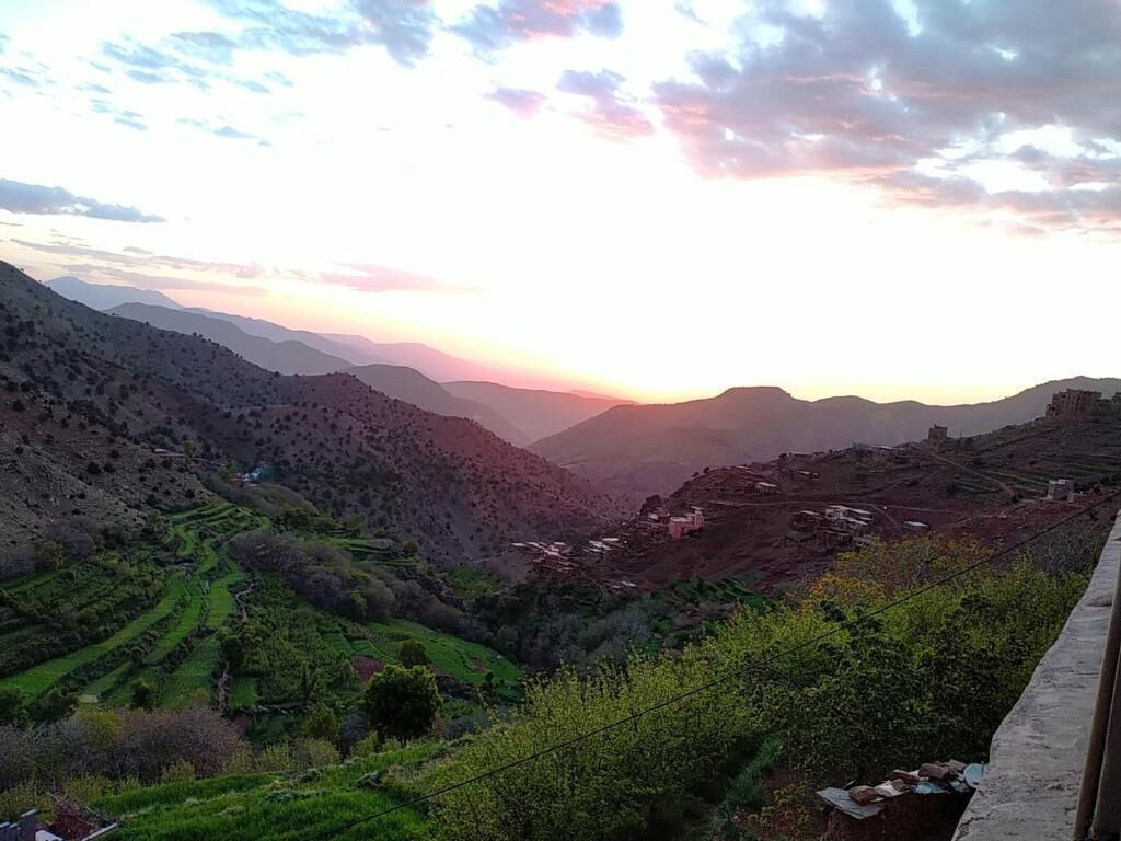 Paisaje montañoso con campos en terrazas y un atardecer.