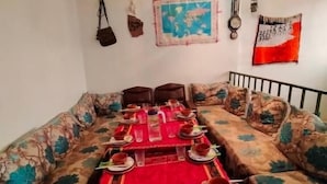 A dining area with a long table set for a meal, surrounded by patterned sofas.