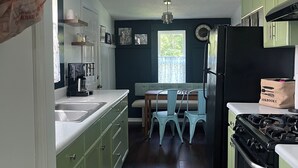 Une cuisine avec des meubles de couleur verte, une cuisinière noire et un tapis bleu.