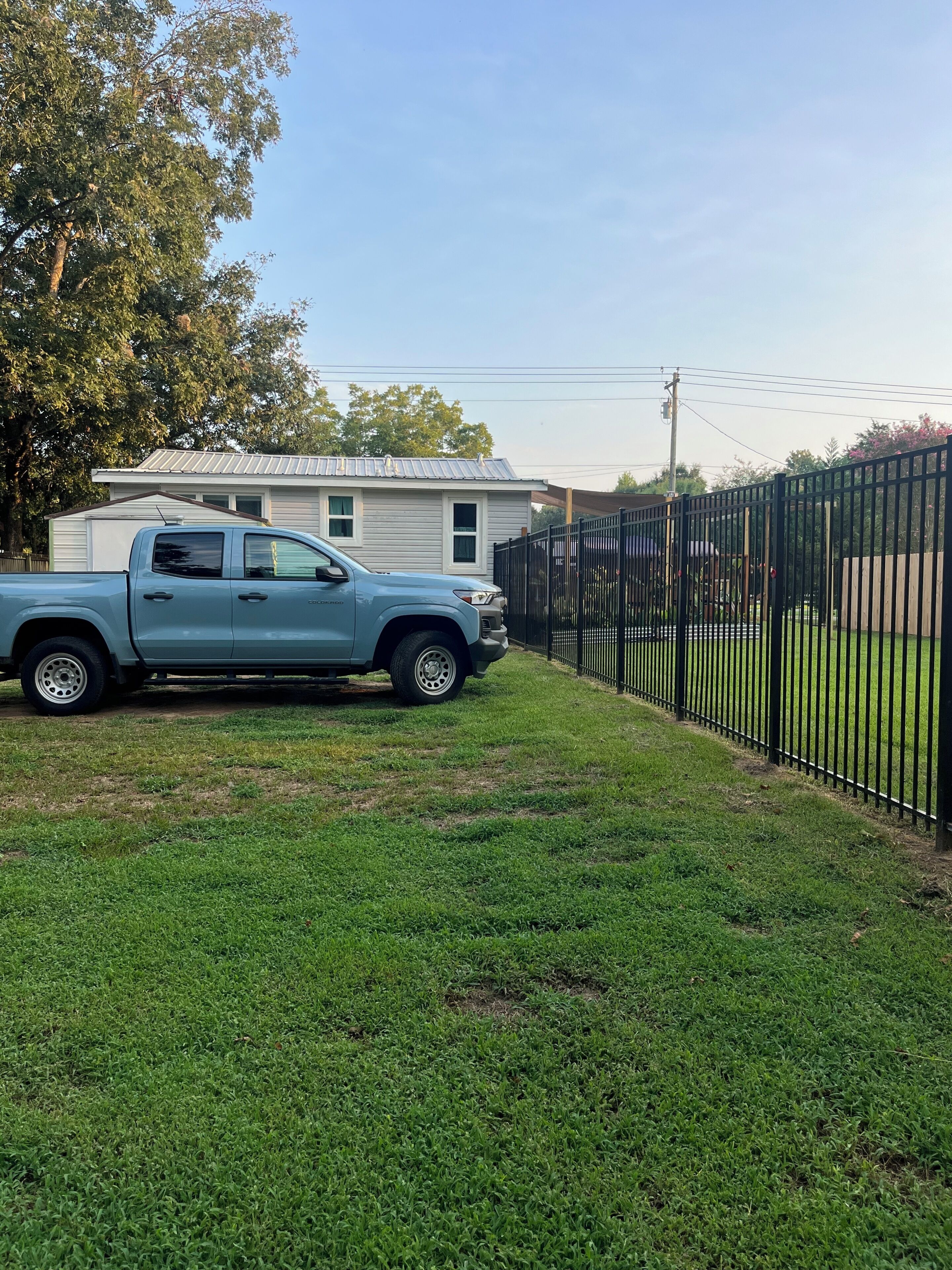 A residential area with a light blue pickup truck parked in front of a house with a metal roof.