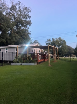 Un barrio residencial con una casa, una terraza de madera y un patio cercado.