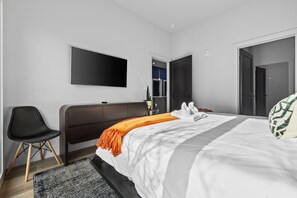 Une chambre d’hôtel moderne équipée d’un lit, d’un téléviseur à écran plat, d’une chaise et d’un bureau.