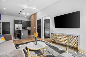 A modern living room with a sofa, a coffee table, and a TV mounted on the wall. - NEW! Chic Designer 2BR w/ Pool / Midtown Townhome (Nashville)