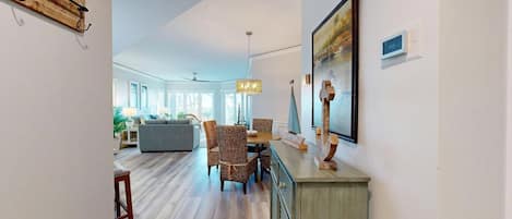 A modern living room with a sofa, chairs, a dining table, and a chandelier.