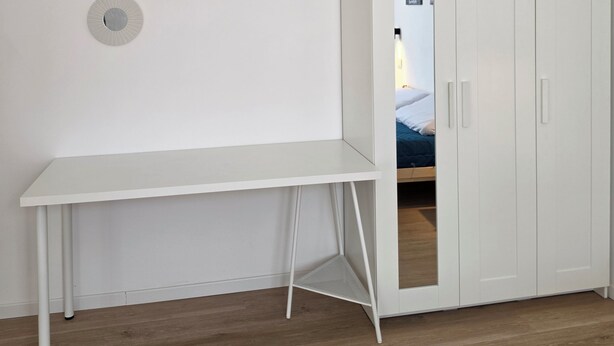 Une pièce comprenant un bureau blanc, une armoire et trois miroirs ronds fixés au mur.