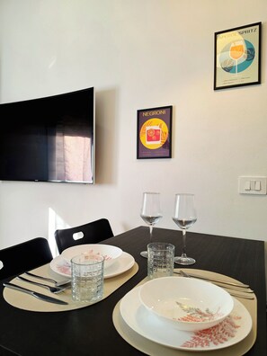 Une table à manger dressée avec des assiettes, des verres, des couverts et un menu encadré.