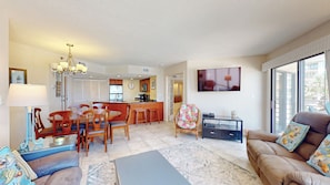 A spacious living room with a dining area, kitchen, and a large window providing a view. - Two Bedroom Second Floor Condominium with Pool and Ocean Views! (Hilton Head)