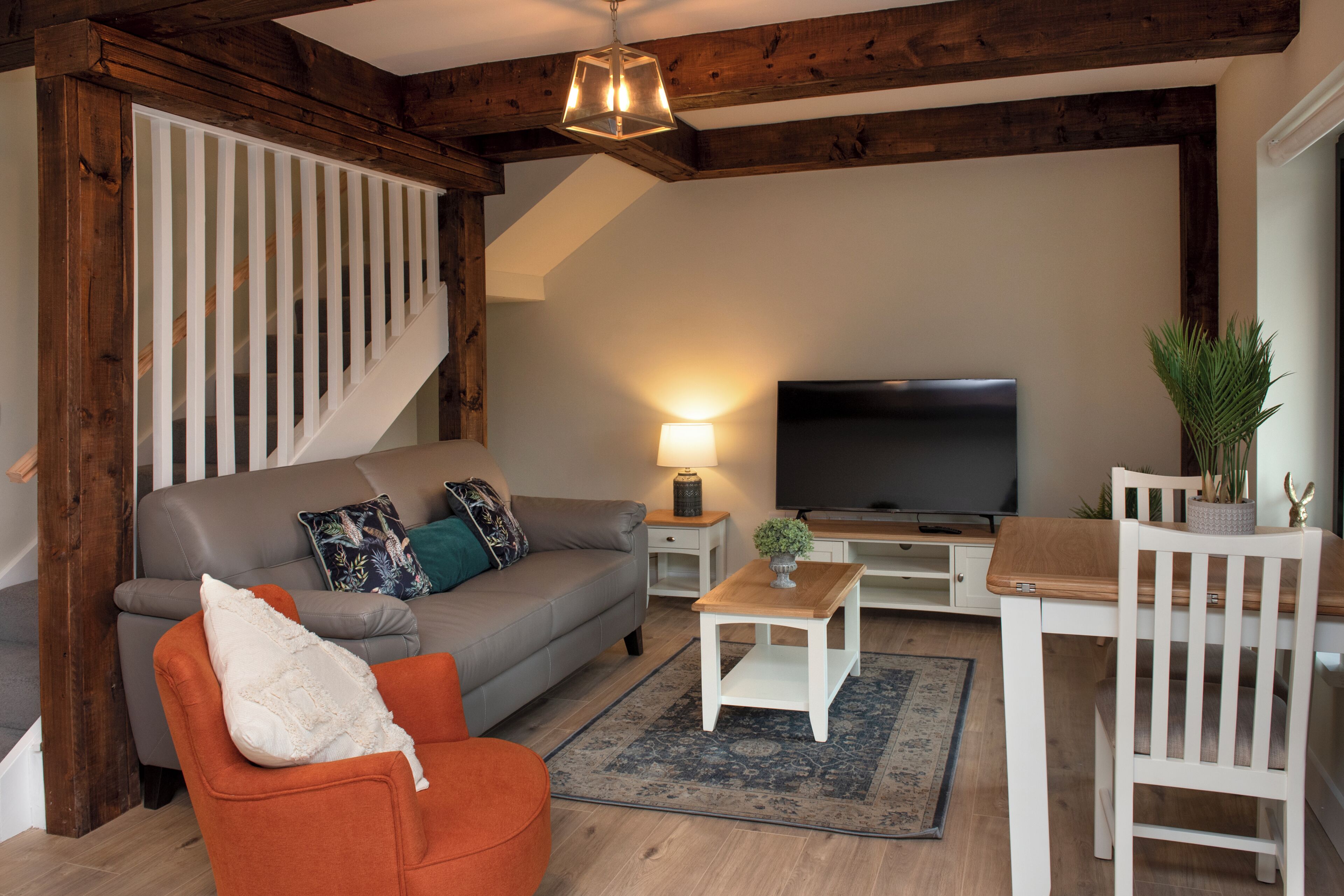 A living room with a sofa, a coffee table, a TV, and a staircase.